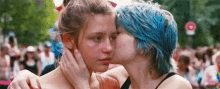 two women are kissing each other in front of a crowd .