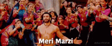 a man without a shirt is dancing in front of a crowd and the words meri marzi are on the screen