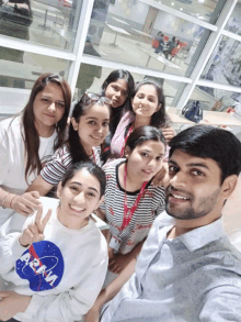 a group of people are posing for a picture with one wearing a nasa sweatshirt