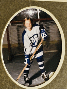 a young boy in a hockey uniform with the letter a on his gloves