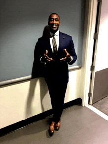 a man in a suit and tie is standing next to a wall