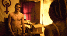 a shirtless man stands in front of a female symbol on a wall