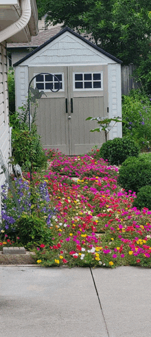 a shed is surrounded by flowers and bushes