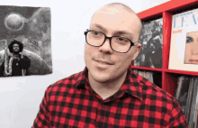 a man wearing glasses and a red and black plaid shirt is standing in front of a dare album