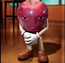 a red apple with arms and legs is sitting on a wooden floor