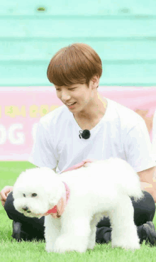 a man kneeling down next to a small white dog with a pink collar