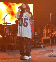 a woman is singing into a microphone while wearing a jersey with the number 05 on it