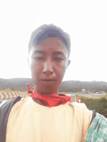 a man wearing a yellow shirt and a red scarf around his neck takes a selfie