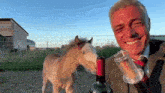 a man in a suit and tie is standing next to a miniature horse and a bottle of wine .