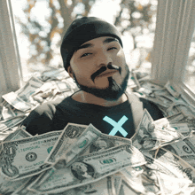 a man in a black shirt with an x on it is surrounded by a pile of money