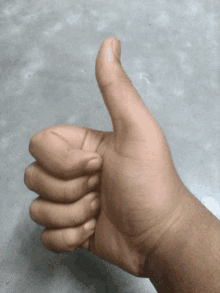 a close up of a person 's hand giving a thumbs up sign