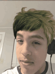 a boy with green hair is wearing headphones and a white shirt