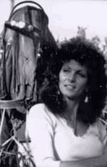 a black and white photo of a woman with curly hair standing next to a boat engine .