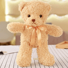 a teddy bear with a bow around its neck is standing on a checkered table cloth