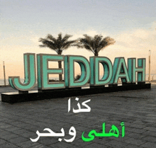 a sign that says jeddah with palm trees behind it