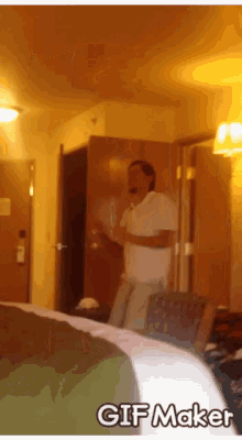 a man in a white shirt is standing in a hotel room with a gif maker watermark