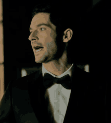 a man in a tuxedo and bow tie looks to the side