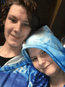 a man and a woman are posing for a picture and the woman is wearing a blue tie dye shirt