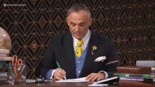 a man in a suit sits at a desk with a stack of books in front of him including one called math