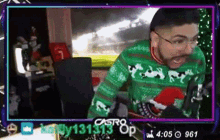 a man wearing a green and red sweater is sitting in front of a computer screen .