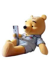 a stuffed winnie the pooh bear is looking at a cell phone