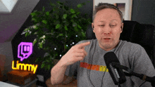 a man sitting in front of a microphone and a sign that says limmy