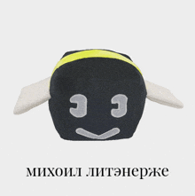 a black and yellow stuffed animal with a face on it and the words михоил written below it