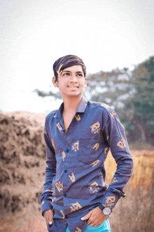 a young man wearing a shirt with the letter r on it stands in front of a pile of hay