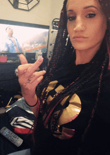 a woman wearing a wu tang t-shirt is giving the middle finger