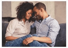 a man and a woman are sitting on a couch and hugging each other .