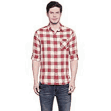 a man wearing a red and white plaid shirt and jeans .