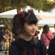 a girl in a black dress with a red bow in her hair is standing in front of a crowd at metrock 2013 special