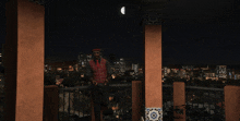 a man standing on a balcony with a city in the background