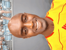 a man wearing a yellow shirt with red stripes on the sleeves is smiling