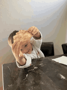 a little boy holds up a piece of bread in his hand