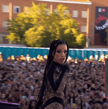 a woman stands in front of a crowd of people with a sign that says ' stadium ' on it