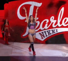 a female wrestler is walking on a stage in front of a sign that says nikki .