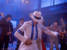 a man in a white suit and hat is dancing in a room