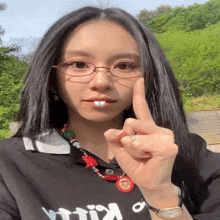 a woman wearing glasses and a necklace with the word kill on it