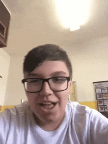 a young man wearing glasses and a white shirt is taking a selfie .