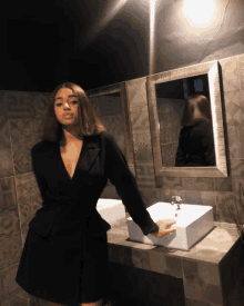 a woman in a black dress stands in front of a sink