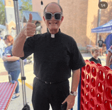 a priest wearing sunglasses and giving a thumbs up