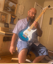 a man with a beard is playing a blue and white guitar