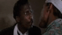 two men are talking to each other in a dark room .