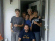 a man wearing a rocky shirt poses for a photo with his family