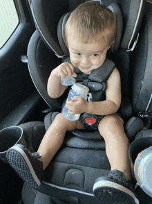 a toddler is sitting in a car seat holding a bottle