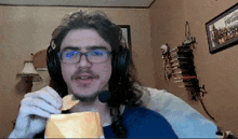 a man wearing glasses and headphones is eating chips