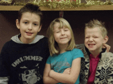 a boy wearing a drummer shirt stands with two other children