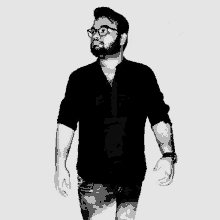 a man with a beard is wearing glasses and a black shirt .