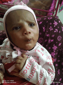 a baby wearing a pink hat and a white shirt that says " emotion " on it